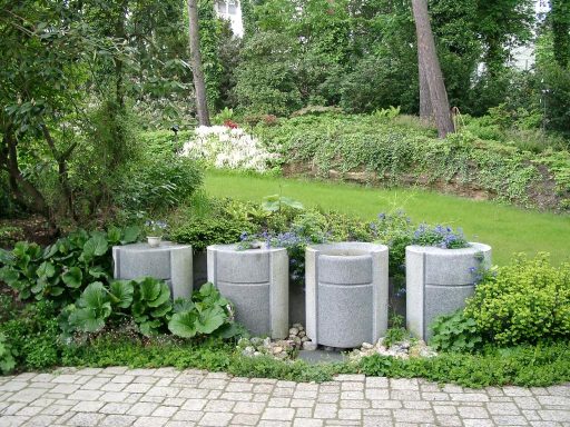 Vier-Quellstein-Brunnen-vor-parkähnlicher-Gartenanlage